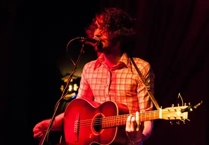 man with a guitar and microphone on a stage