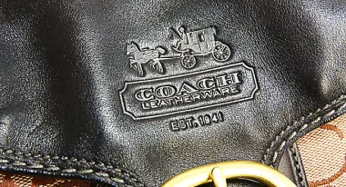 Close up of a Coach purse leather logo